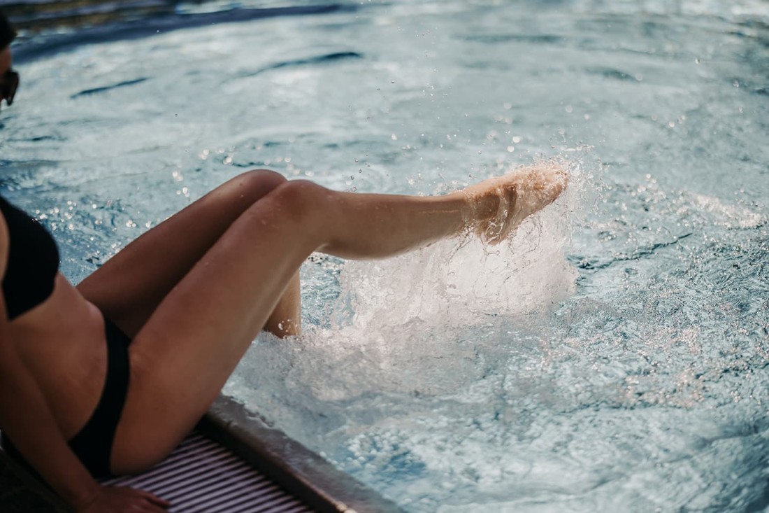 Eine Person spritzt Wasser im Pool mit ihrem Bein
