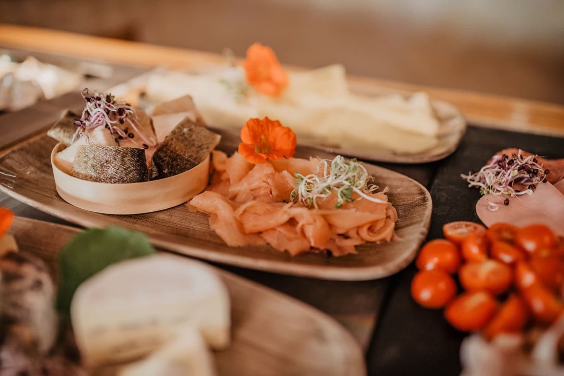 Verschiedene Antipasti auf h&ouml;lzernen Tellern mit Fisch, Tomaten und Kr&auml;utern