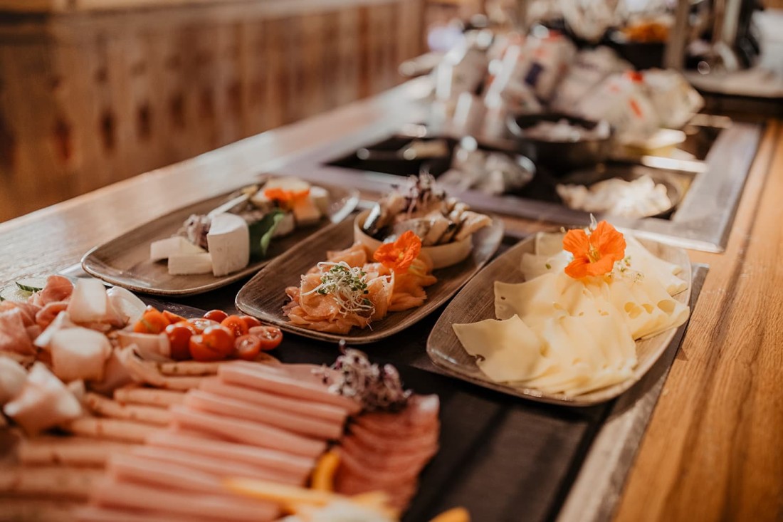 Verschiedene K&auml;sesorten und Wurst auf Holzplatten dekoriert mit Blumen