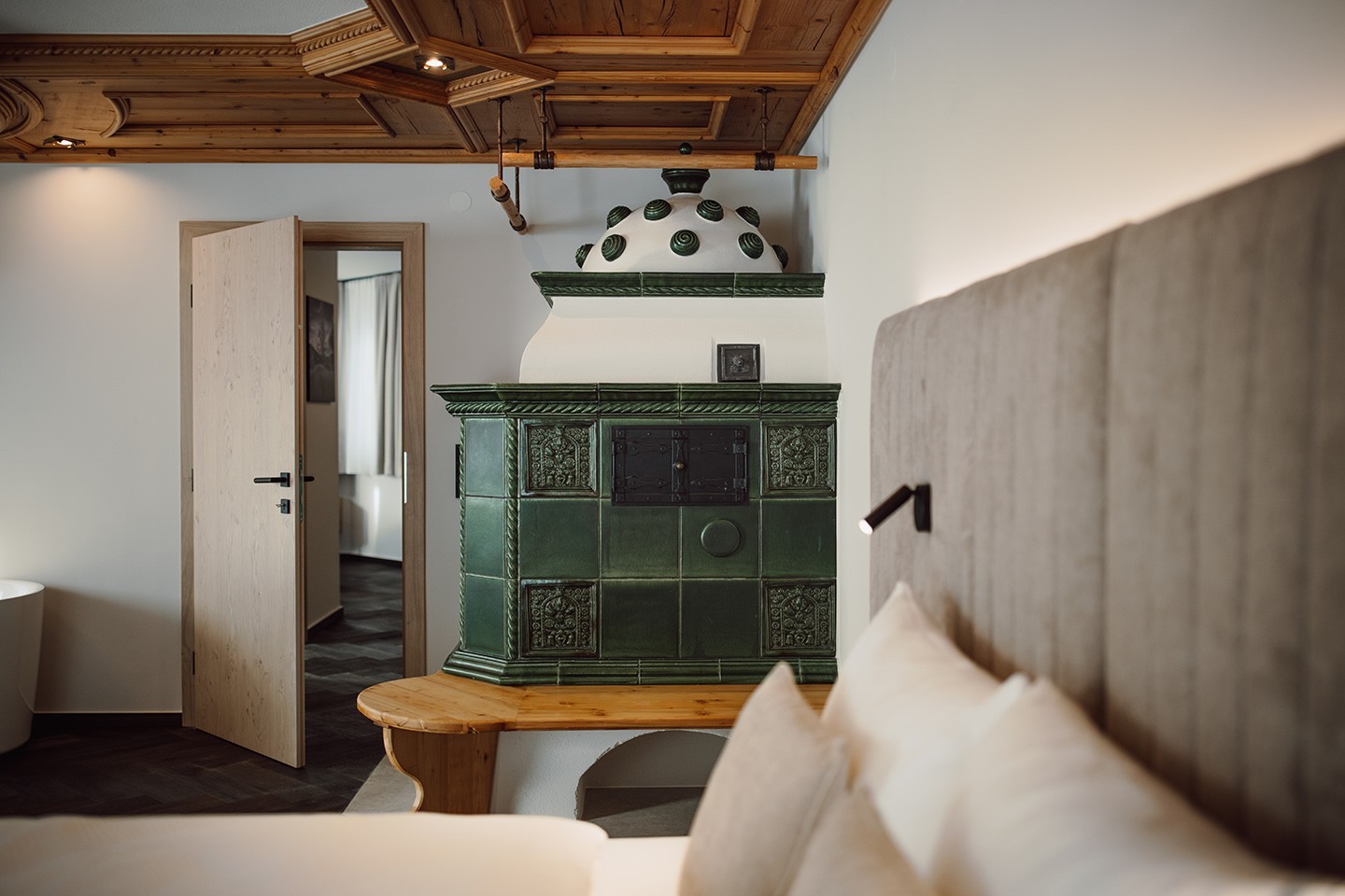 Doppelbett und Kachelofen in der Gartensuite